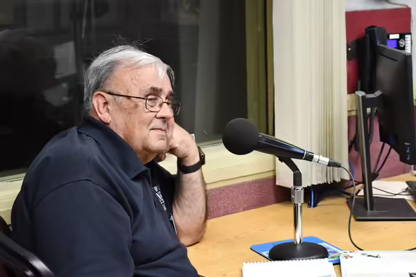 John Bodensteiner sitting next to a microphone listening to someone offscreen.