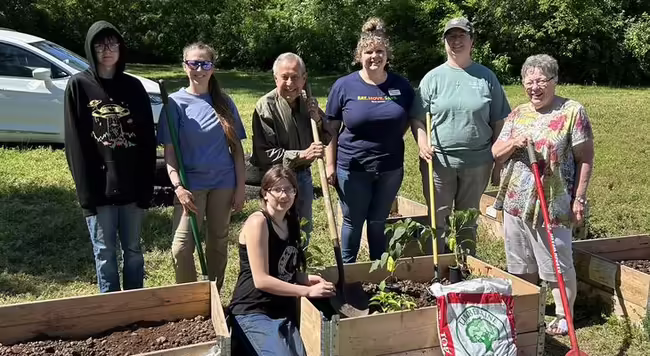 a group of volunteers pose by a community garden