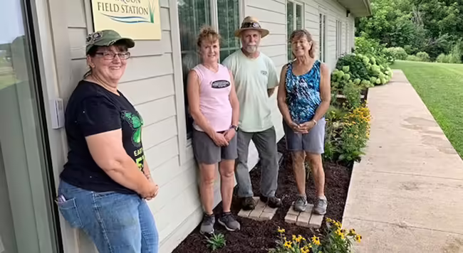four people standing in front of building and new landscaping